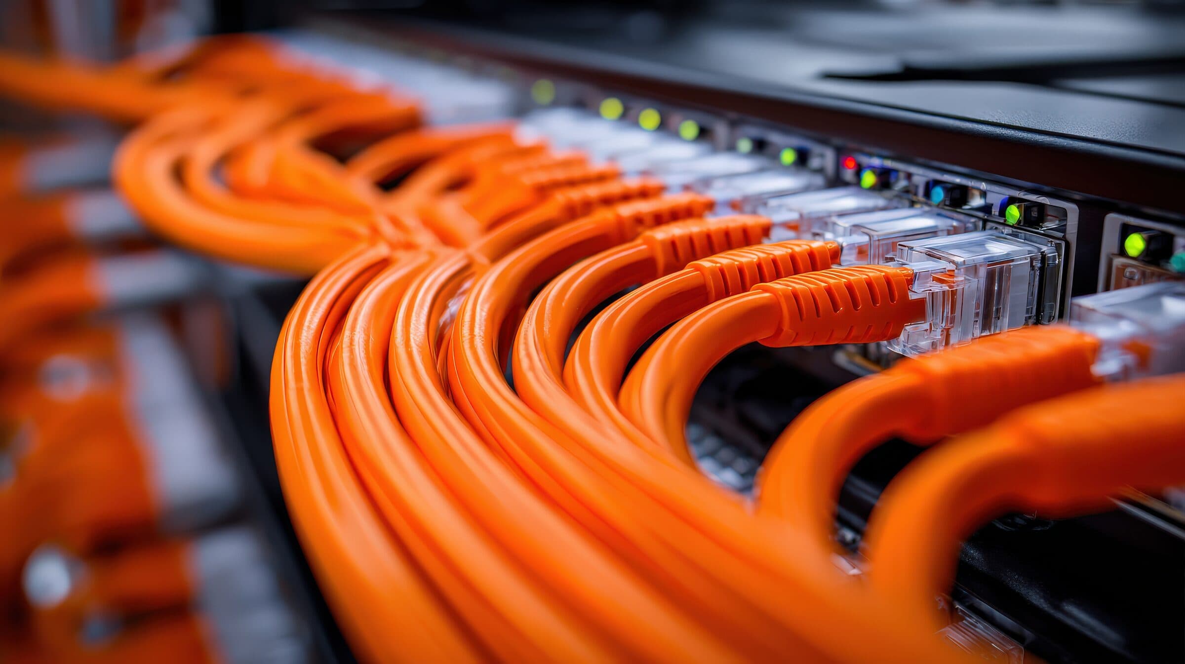 Orange network cables plugged into a row of switch ports, with green status lights glowing